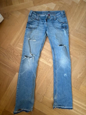Ljusblå slitna jeans - Säljer ett par låg midja ljusblå jeans med raka/utsvångda