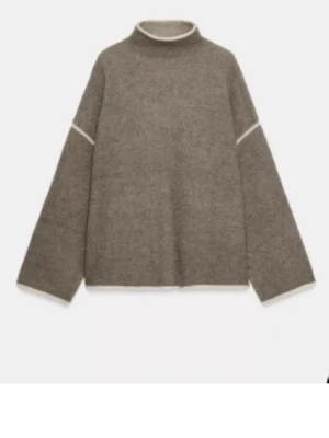 Brun stickad tröja med vita detaljer - En efterlängtad tröja från Zara!! Storlek M men sitter som S. En oversized brun stickad tröja med vita kontrastsömmar vid hals, ärmar och nederkant. Tröjan har hög hals och vida ärmar, perfekt för att skapa en chill och trendig look. Materialet ser ut att vara mjukt och varmt, idealiskt för kalla dagar.