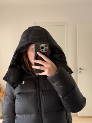 Svart pufferjacka från Calvin Klein - Svart pufferjacka från Calvin Klein Jeans med huva och dragkedja framtill. Säljer pågrund av att den inte kommer till användning hos mig. Den är i storlek M men passar S