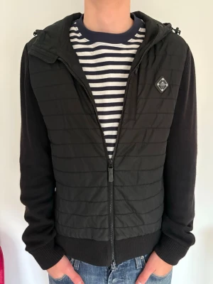 J Lindeberg Cardigan - Säljer denna snygga cardigan då den börjar bli för liten. Köpte ny för 3200kr och säljer nu för endast 999! Pris kan diskuteras vid snabb affär. Finns ett litet hål på framsidan som inte syns och ett igensytt hål i fickan som man inte lägger märke till, skriv för bilder! Hör av er vid minsta fundering 