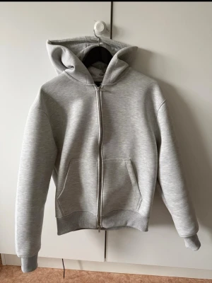 Ljusgrå zip oversized hoodie (storlek XS/S) - Säljer en stilren ljusgrå hoodie i storlek XS men är stor i storlek, personligen tycker jag att det är en S. Oversized, med andra ord.  Den har  dragkedja framtill och två stora fickor. Perfekt för en avslappnad. Endast testat hoodien 2 gånger. 