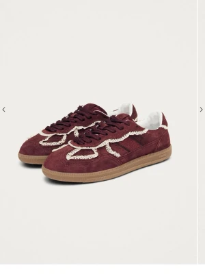Vinröda sneakers med spetsdetaljer - Unika vinröda sneakers från Alohas i mocka med vita spetsdetaljer längs kanterna och klassisk gummisula. Skorna har mörkröda skosnören och låg profil som ger en cool och trendig vibe. Köpte dom i London men kom alldrig till användning Perfekta för dig som vill sticka ut med din stil.