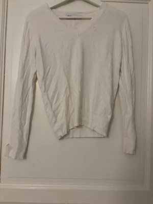 Vit V-ringad långärmad tröja - Vit långärmad tröja från Zara med V-ringning och enkel design. Tröjan har en rak passform och är tillverkad i ett mjukt tyg som passar perfekt till jeans eller kjol.