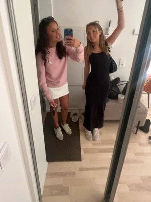 Svart långklänning med smala axelband - En elegant svart långklänning med smala axelband och figurnära passform. Klänningen har en enkel och stilren design som framhäver siluetten. Perfekt för dig som gillar klassiska och tidlösa plagg.