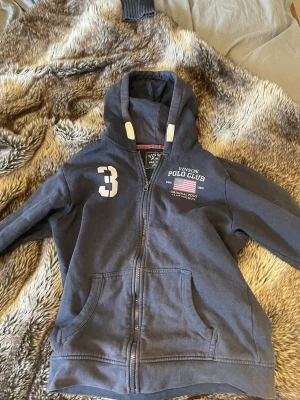 Mörkblå hoodie från Vinson Polo Club - Mörblå hoddie från polo club med USA 🇺🇸 detaljer. Hoddien passar 12-13y. Slå bara en pling 🛎️ kring några funderingar.