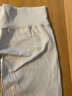 Ljusblå ribbade leggings från ICANIWILL - Säljer ett par ljusblå leggings från ICANIWILL med ribbad struktur och hög midja. De är stretchiga och har en diskret logga framtill. Perfekta för träning eller chill dagar. Materialet känns mjukt och följsamt.