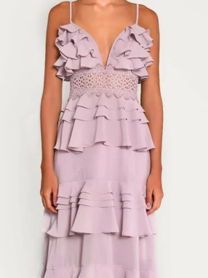 Ljuslila volangklänning med spets - Säljer en lång, ljuslila klänning med tunna axelband, djup v-ringning och flera lager volanger. Klänningen har en vacker spetsdetalj i midjan och är perfekt för speciella tillfällen och baller. Materialet känns lätt och luftigt. Pris går att diskutera!