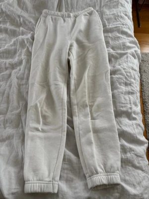 Vita mjukisbyxor med resår - Säljer ett par vita mjukisbyxor med resår i midjan och vid bensluten. Byxorna har en avslappnad passform och är tillverkade i ett mjukt och bekvämt material, perfekta för chill dagar hemma. Fickor på sidorna för extra funktionalitet🤍Har svaga fläckar (de på bilderna)😚
