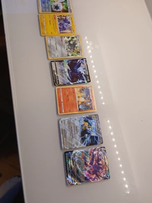 Samling Pokémonkort blandade typer - Säljer en samling Pokémonkort med olika typer och motiv. Bland korten finns både vanliga och holografiska kort med färgstarka illustrationer. Perfekt för dig som vill utöka din samling eller gillar Pokémon. Kort i olika färger och med olika Pokémon.