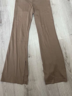 Bruna vida leggings från 157 - Säljer ett par bruna leggings från 157 med vida ben och slits nertill. Tillverkade i mjukt material med 90% viskos och 10% elastan för extra stretch och komfort. Perfekta för en avslappnad och trendig look. Använt mindre än 5 gånger