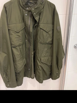 Polo Ralph Lauren Field Jacket - Grön fodrad field jacket från Polo Ralph Lauren i nylon. Perfket till vår/höst. Storlek L. Mycket lätt och går att packa ner i sin egen ficka. Inte använd mycket och är i mycket fint skick. Nypris 5 395 kr.