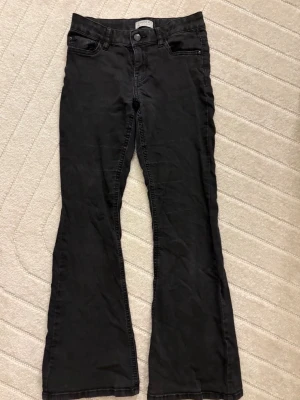 Svarta lågmidjade utsvängda jeans från Lindex  - Svarta bootcut jeans från Lindex. Säljer eftersom jag växt ur dem. De har blivit lite urtvättade och det finns spår av mitt namn på lappen innuti jeansen💕