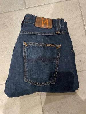 Mörkblå raw denim jeans från Nudie Jeans - Säljer ett par mörkblå jeans från Nudie Jeans i modellen Sharp Bengt som är discountied jeans är även avklippta . Tillverkade i slitstark denim, perfekta för en avslappnad stil. Storlek 30/30