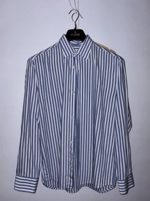 Blåvit randig skjorta från NN.07 - Säljer en klassisk blåvit randig skjorta från NN.07. Skjortan har knappar framtill, lång ärm och en snygg krage. Nypris 1600:-. Burit den en gång