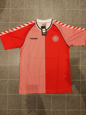 Matchtröja L Danmarks landslag DBU 1986 retro - Retro matchtröja danska landslaget DBU i modell från 1986. Tröjan är en reprint och aldrig använd. Storlek L (se mått bland bilderna).
