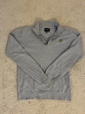 Grå halvziptröja från Lyle & Scott - Snygg grå tröja från Lyle & Scott med halv dragkedja och klassisk gul logga på bröstet. Tillverkad i mjukt material som känns skönt mot huden. Tröjan är i storlek 164cm och i mycket bra skick✅ Fraktar inom en dag✅ Priset är inte hugget i sten🙂