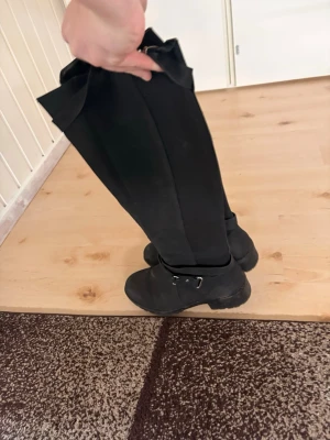 Svarta höga stövlar med spänne som är fina - Säljer ett par svarta höga stövlar med dekorativa spännen i silverfärg vid ankeln och skaftet. Stövlarna har en robust sula och är tillverkade i ett matt material som är fett mjuk skön och fin inga användning täcken använd några gånger men vill ej ha de helt nya ungefär