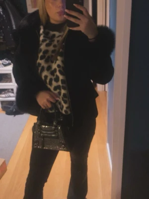 Leopardmönstrad stickad tröja - Säljer en snygg stickad tröja med leopardmönster i svart och beige. Tröjan har en avslappnad passform och är perfekt för dig som vill sticka ut med ett djuriskt print. Materialet är mjukt och skönt, passar till både jeans och kjol.