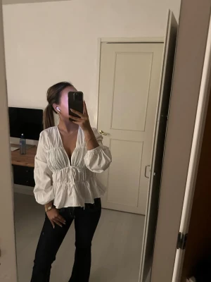 Vit v-ringad blus med puffärm - Trendig vit blus med djup v-ringning och bred resår i midjan som ger en snygg siluett. Från Hm och i storlek xs