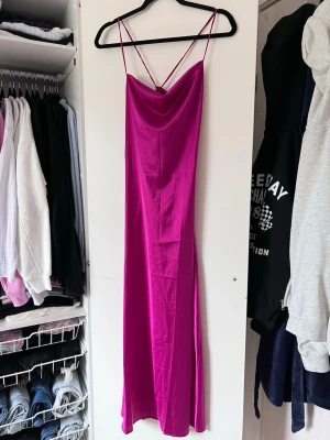 Rosa satinklänning med smala axelband - Snygg rosa långklänning i satin med smala axelband och knytning i ryggen. Perfekt för en somrig look med sin glänsande finish och eleganta design. Använd 1 gång 🩷