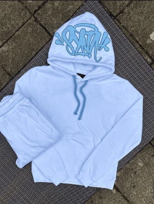 Ljusblå hoodie set med graffiti - Säljer ett ljusblått loungewear-set med hoodie och matchande byxor. Hoodien har en cool graffiti-text i blått på huvan och snören i samma färg. Perfekt för chill dagar hemma eller när du vill vara bekväm men ändå se snygg ut.