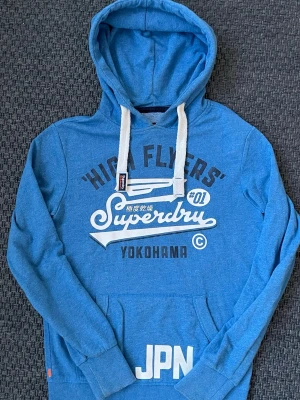 Vintage 2000s SuperDry hoodie (JPN EDITION) - Säljer nu denna sjukt snygga och sällsynta vintage 2000s hoodie från SuperDry 😊 Den är ur en limiterad upplaga och säljs ej längre, därav mycket eftertraktad 🙌 Riktigt varm och bekväm så passar perfekt till våren🤝Skicket är som nytt! Skriv vid funderingar 📲🤩