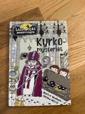 LasseMajas Detektivbyrå: Kyrkomysteriet - En spännande och illustrerad bok i serien LasseMajas Detektivbyrå, skriven av Martin Widmark och illustrerad av Helena Willis. Omslaget är färgglatt med motiv från en kyrka och boken är inbunden. Perfekt för dig som gillar mysterier och äventyr.