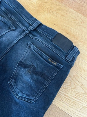 Nudie jeans svart/grå -  Nudie jeans.        Snygga svarta slim jeans med klassisk femficksdesign och kontrastsömmar. Jeansen har en smal passform och är tillverkade i stretchigt denimtyg för extra komfort. Perfekta för en trendig och avslappnad stil. W32 L34