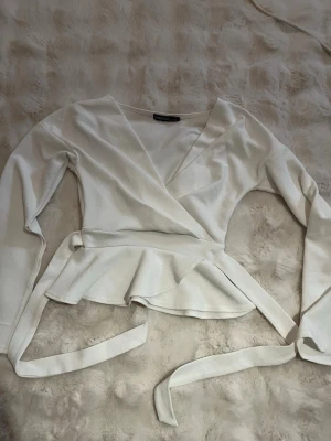 Vit omlottblus från Bonprix - Snygg vit omlottblus från Bonprix med långa ärmar och knytband i midjan. Tröjan går in i midjan och går också att spänna åt. Passar både till enkla outfits men också uppklädda💕 