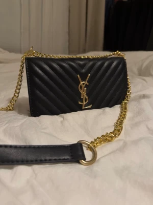 YSL väska - !! RESERVERAD !! Mycket fin väska med YSL märke. Den är köpt i Spanien, säljs då den ej kommer till användning. Kvaliteten är mycket bra. Inga defekter osv