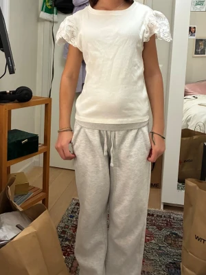 Vit blus med spetsärmar - Söt vit blus med korta, vida ärmar i spetsdetalj. Toppen har rund halsringning och är i ett mjukt bomullsmaterial. Perfekt för dig som gillar en feminin och enkel stil. Kan diskutera priset