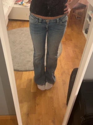 Blå bootcut jeans med låg midja - Säljer ett par jättefina ljusblå bootcut jeans med låg/lägre mellan midja, kan såklart sy midjan kortare enkelt. Klassiska fem fickor och diamanter på baksidan. Jeansen har en snygg tvätt och utsvängda ben, perfekta till sneakers eller boots. Materialet är denim i bomull och de har bälteshällor och knappgylf. Säljer för att de var liiiite för stora för mig. Står storlek 164, vilket är ungefär s❤️använda endast en gång och original priset var run 300-350kr