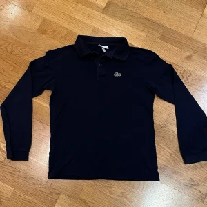 Lacoste piké  - Säljer en Lacoste piké långärmad i storlek 152cm/12. Den är inte så använd. Vet inte riktigt nypris men är mycket dyrare än vad jag säljer den för. Tröjan har inga defekter som jag kan se. Skriv vid minst fundering!
