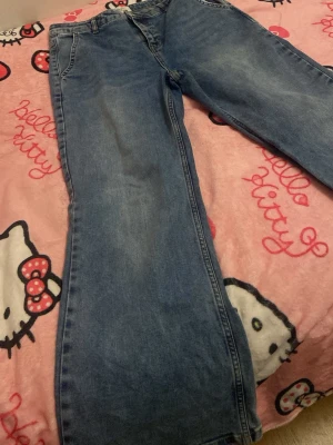 Blåa bootcut jeans med vintagekänsla - Säljer ett par blåa jeans med lite bootcut  passform och klassisk femficksdesign. Jeansen har en lätt tvättad look och är tillverkade i denim. Perfekta för dig som gillar en avslappnad och tidlös stil.