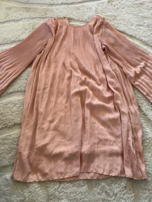 Ljusrosa plisserad klänning Bik Bok - Söt ljusrosa klänning från Bik Bok i storlek XS. Klänningen har plisserade långärmar och en lös passform med rund halsringning. Materialet känns lätt och flowy, perfekt för vår och sommar.