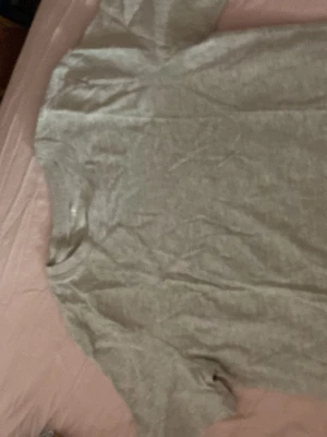 Grå basic t-shirt från H&M - En enkel och stilren grå t-shirt från H&M i mjuk bomull. T-shirten har korta ärmar och rund halsringning, perfekt för en clean och avslappnad look. Passar till allt och är ett måste i garderoben.