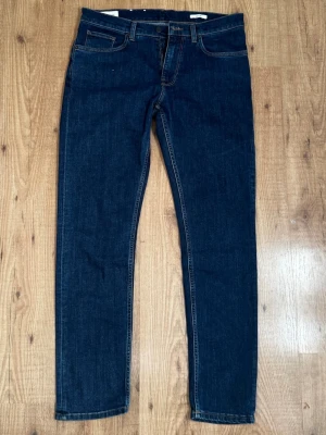 Mörkblå raka jeans från Gant - Snygga mörkblå jeans från Gant med klassisk femficksmodell och raka ben. Jeansen har kontrastsömmar och en enkel, stilren look som passar till det mesta. Tillverkade i mjuk denim med skön stretch för extra komfort.