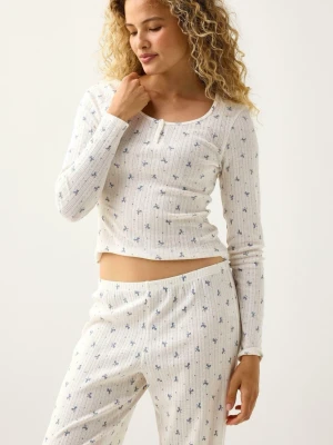 Vit ribbad pyjamas med blå blommor - Supermysig vit ribbad pyjamas med små blå blommor och långärmad topp med knappdetalj vid halsen. Byxorna har en avslappnad passform och samma blommiga mönster.  