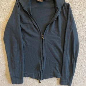 Grön/blå zip från Oscar Jacobson - Grön/blå zip kofta från Oscar Jacobson med hel dragkedja framtill. Tillverkad i Italien och i ett mjukt, stickat material. Klassisk passform med långa ärmar och enkel design, perfekt att slänga på sig över en t-shirt.dne har tre skador so vissas på bilderna 😁