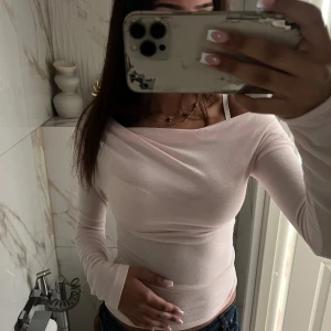 Ljusrosa offshoulder topp Nelly - Säljer en ljusrosa offshoulder topp med lång ärm och tight passform. Toppen är helt slutsåld i S på hemsidan och är i nytt skick med prislapp.