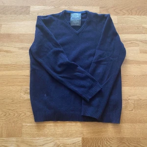 Mörkblå ulltröja från Springfield - Mysig mörkblå tröja från Springfield i 100% ull. Klassisk v-ringad modell med ribbade muddar vid ärmslut och nederkant. Perfekt för kyliga dagar och enkel att matcha med jeans eller chinos. Det står XL på etiketten men den har dock krympt vilket gör att den nu passar M/L bättre.