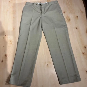 Beige kostymbyxor från Cavaliere - Snygga beige kostymbyxor från Cavaliere med klassisk rak passform. Byxorna är tillverkade i en skön mix av 60% ull och 40% polyester, vilket ger en stilren look och bra komfort. Perfekta för dig som vill ha en clean och dressad stil.