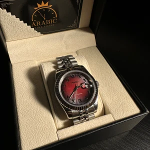 Seiko Red Rosé Mod Klocka - Säljer en stilren Seiko klocka med automatisk urverk, red rosé urtavla med arabiska siffror och datumvisning samt luminous handvisare. 39 mm klockan med ett klassiskt rundat silverfärgat boett och länkarmband i 904L stäl. Glas pa bada sidorna gjort av safir vilket innebär att den är reptälig. Perfekt accessoar för dig som gillar snygga detaljer och modern design.