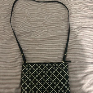 Malene Birger - Snygg axelväska med svart botten och vitt geometriskt mönster. Väskan har en justerbar axelrem i svart och stängs med dragkedja upptill. Perfekt storlek för det viktigaste och stilren design som sticker ut. Materialet känns som syntet och är lätt att hålla rent.