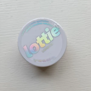 Lottie London Golden Hour ögonskugga - Säljer en metallic ögonskugga från Lottie London i färgen Golden Hour. Skuggan har en intensiv guldig nyans med metallisk finish och kommer i en rund plastburk på 2g. Vegansk och cruelty free – perfekt för dig som vill ha glow på ögonlocken.