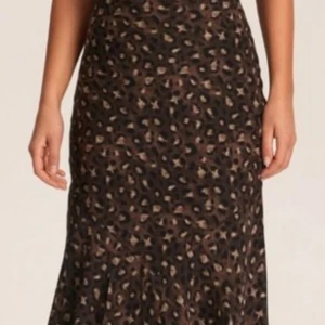 NY - Adoore Leopardmönstrad långklänning - Supersnygg långklänning från Adoore med leopardmönster i bruna och svarta toner. Klänningen har tunna axelband, öppen rygg med snörningsdetalj och figurnära passform. Perfekt för dig som vill sticka ut med en trendig look. Ny med prislapp!
