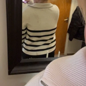 Randig vit och marinblå half zip tröja - Säljer en vit tröja med marinblå horisontella ränder och half zip-dragkedja vid kragen. Tröjan har långa ärmar, ribbade muddar och en avslappnad passform. Perfekt för dig som gillar en klassisk och chill stil. Har lite fläckar 