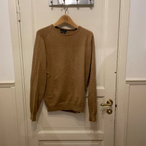 Beige kashmirtröja från Massimo Dutti - Snygg beige stickad tröja från Massimo Dutti i bomull och kashmir. Tröjan har rund hals, långa ärmar och mockadetaljer på armbågarna för en extra stilren touch. Perfekt för lager-på-lager under hösten och vintern. Kashmire blandning 