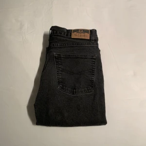 Svarta jeans från McGordon, 31/30 - Svarta jeans från McGordon med klassisk femficksdesign och hög midja. Jeansen har raka ben och en snygg svart tvätt som passar till det mesta. Materialet är slitstarkt jeans och de har en enkel, stilren look med läderpatch bak.