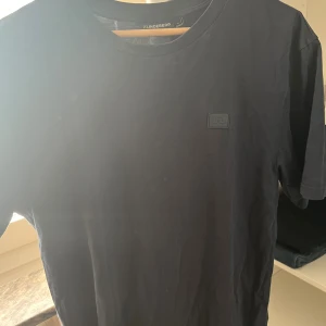 Marinblå t-shirt från J.Lindeberg - Svart t-shirt från J.Lindeberg i mjuk bomull med klassisk passform. T-shirten har rund halsringning och en diskret logotyp-patch på bröstet. Enkel och stilren design som funkar till allt.